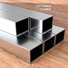 Stacked metal square tubes on wooden surface, labeled 50x50mm, 1.8mm thickness.