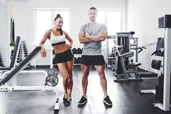 A man and a woman posing at the gym