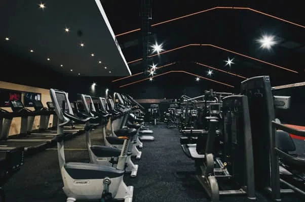 Modern gym with exercise machines and dim lighting.