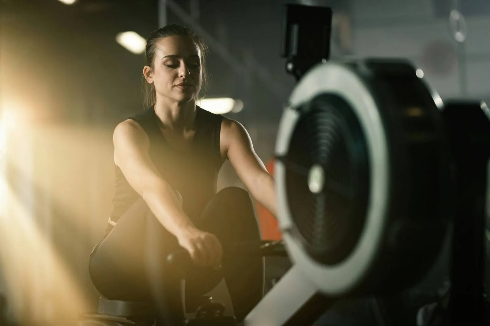 Woman exercising on a rowing machine in a gym.
