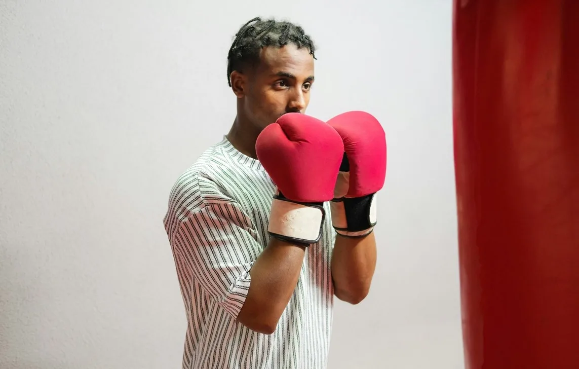 Young boxer wearing red gloves in fighting stance during training.