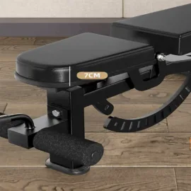 Adjustable black workout bench with 7cm height setting on wooden floor.
