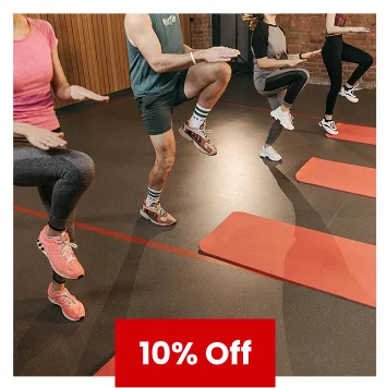 Group fitness class performing warm-up exercises on red yoga mats with 10% off offer.