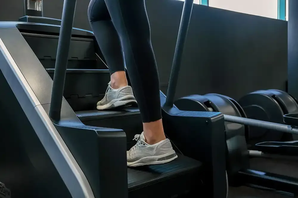 Person using stair climber machine for lower body and cardio fitness training.